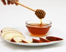 Apple slices and bowl of honey on a plate