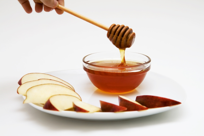 Apple slices and bowl of honey on a plate